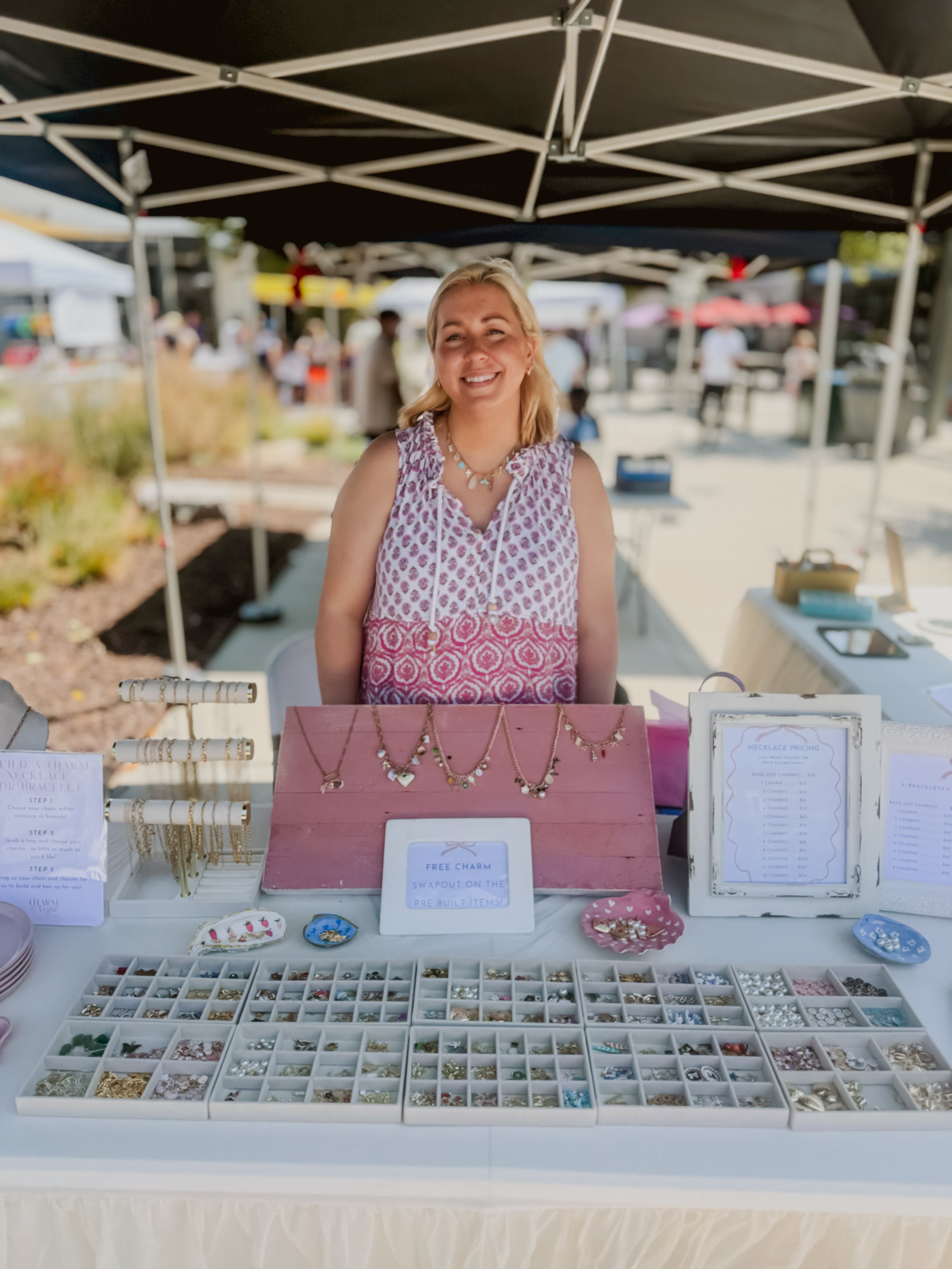 Woman standing behind a jewelry booth at an outdoor market