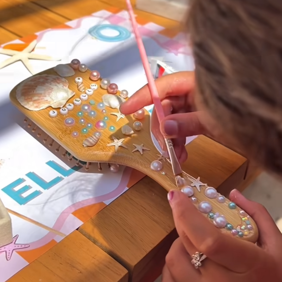 Person holding a decorative hairbrush with a blurred outdoor setting in the background