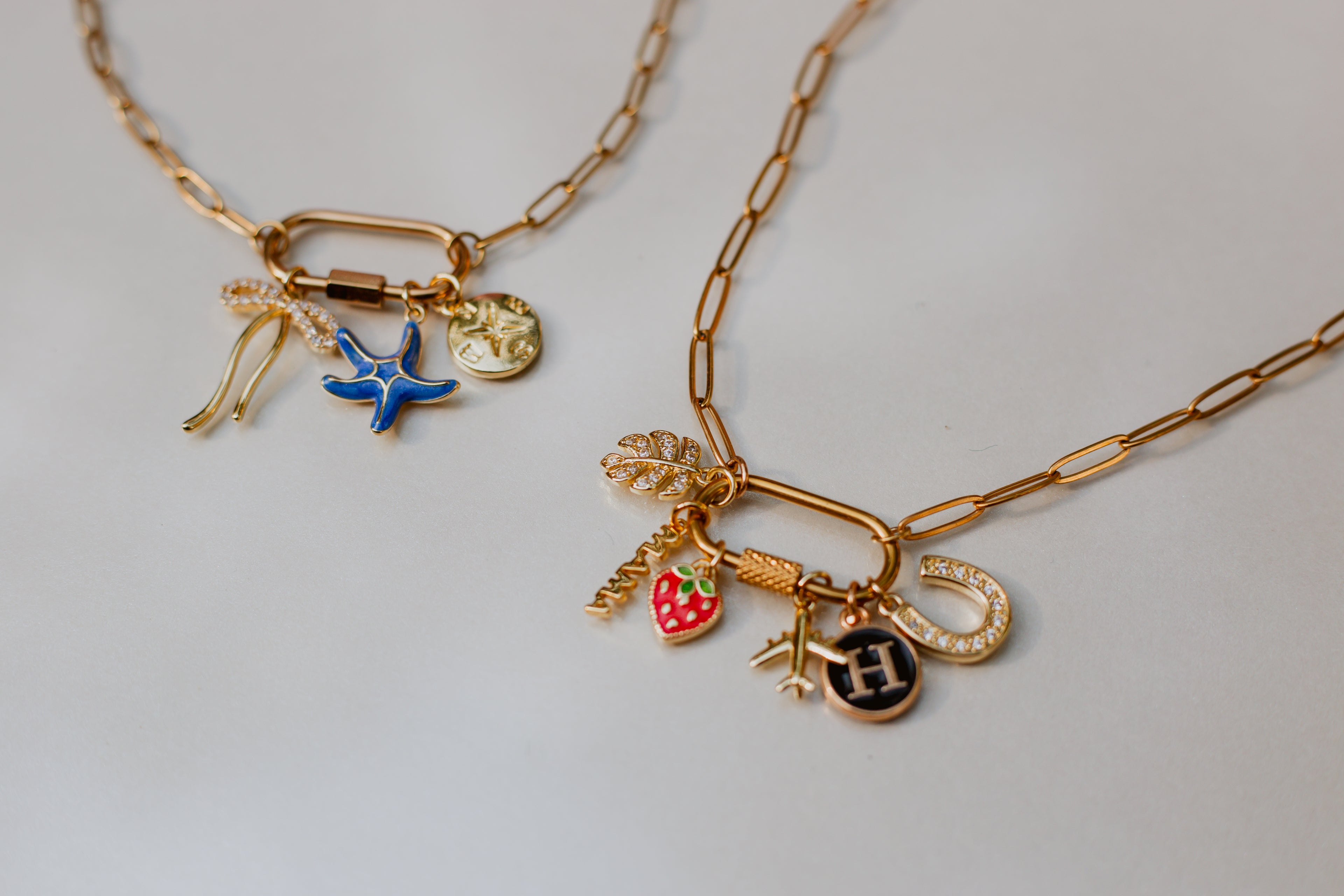 Gold necklaces with various charms on a light gray background