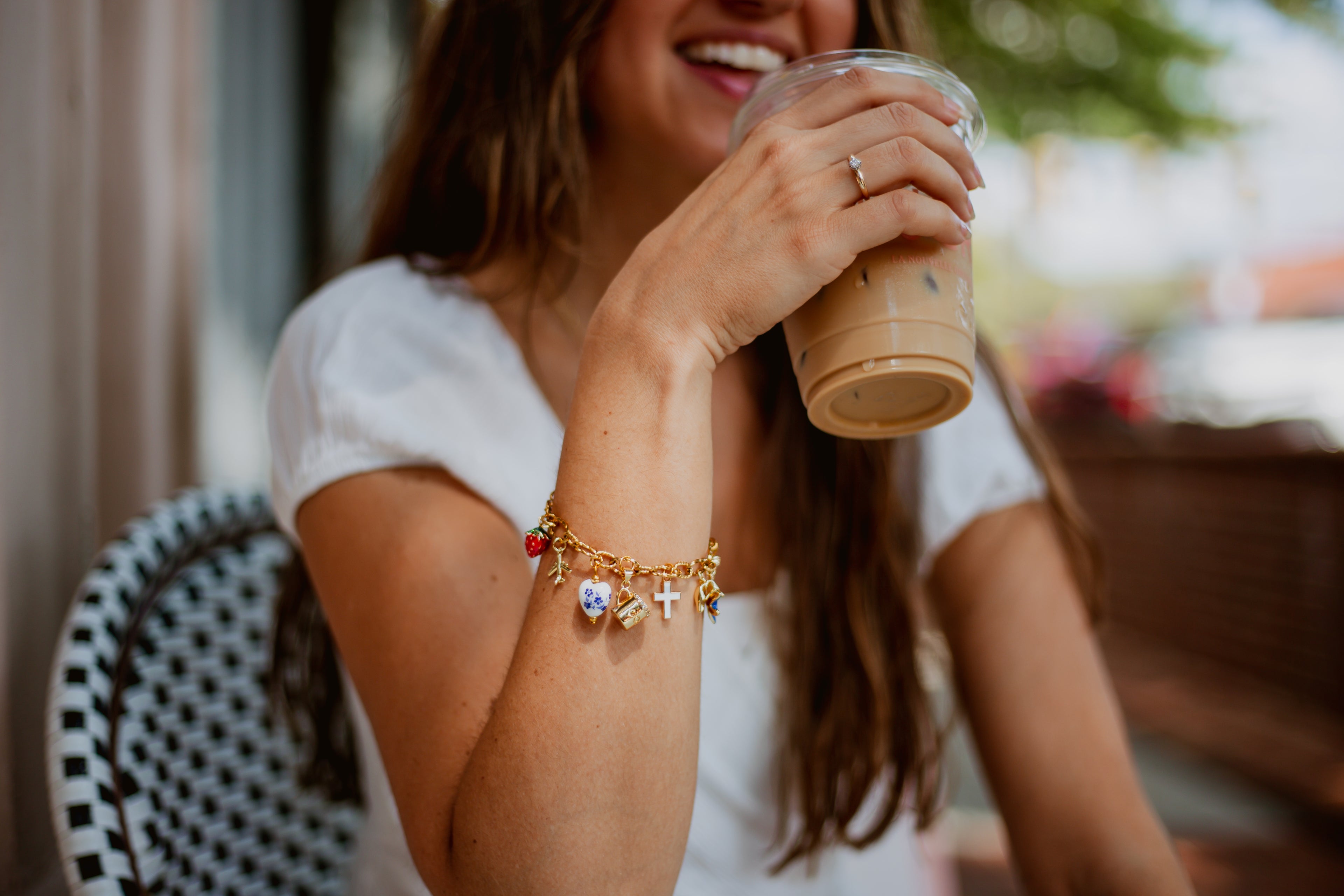 Woman holding a coffee cup outdoors with charm bracelet