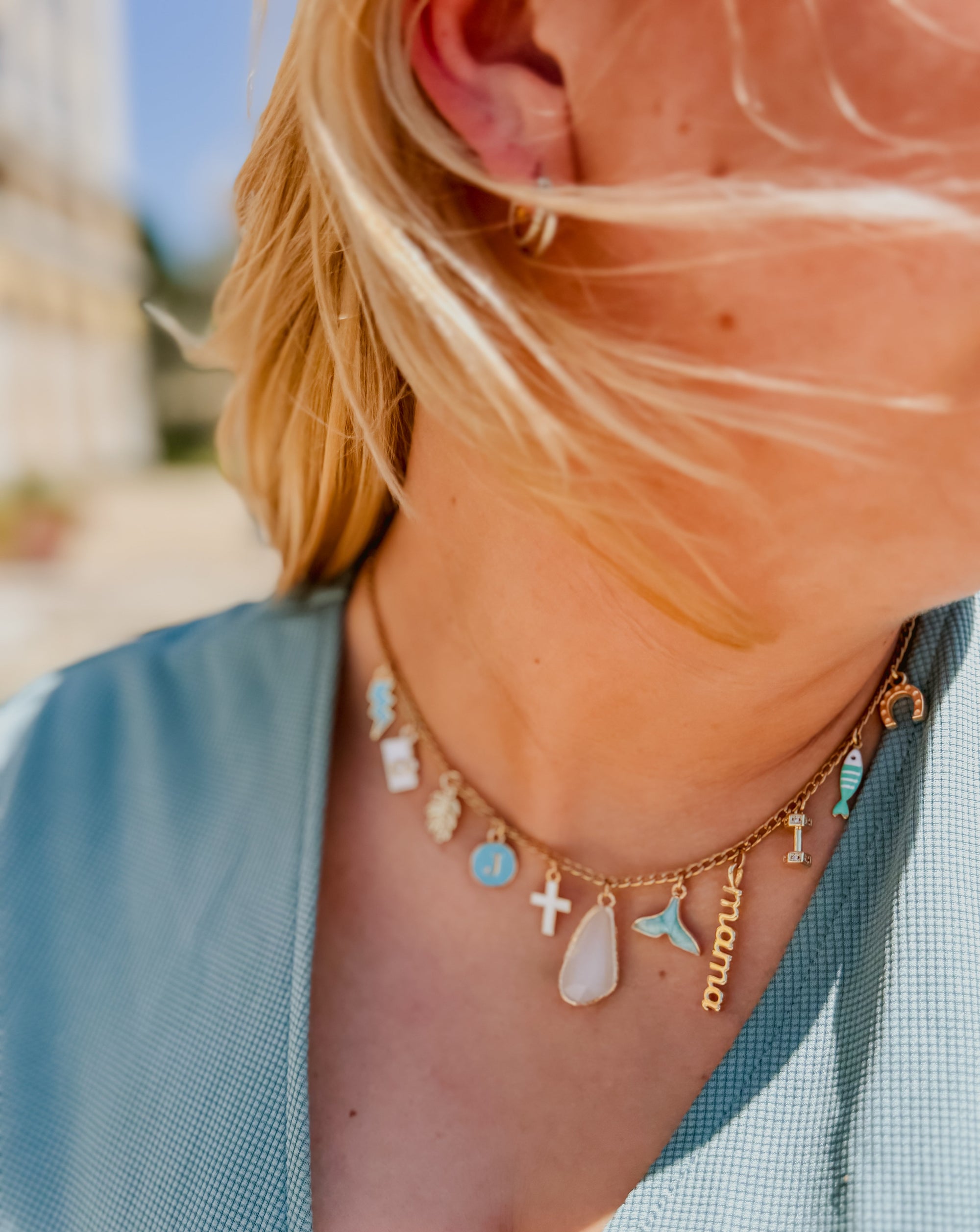 Close-up of a person wearing a necklace with various charms outdoors.