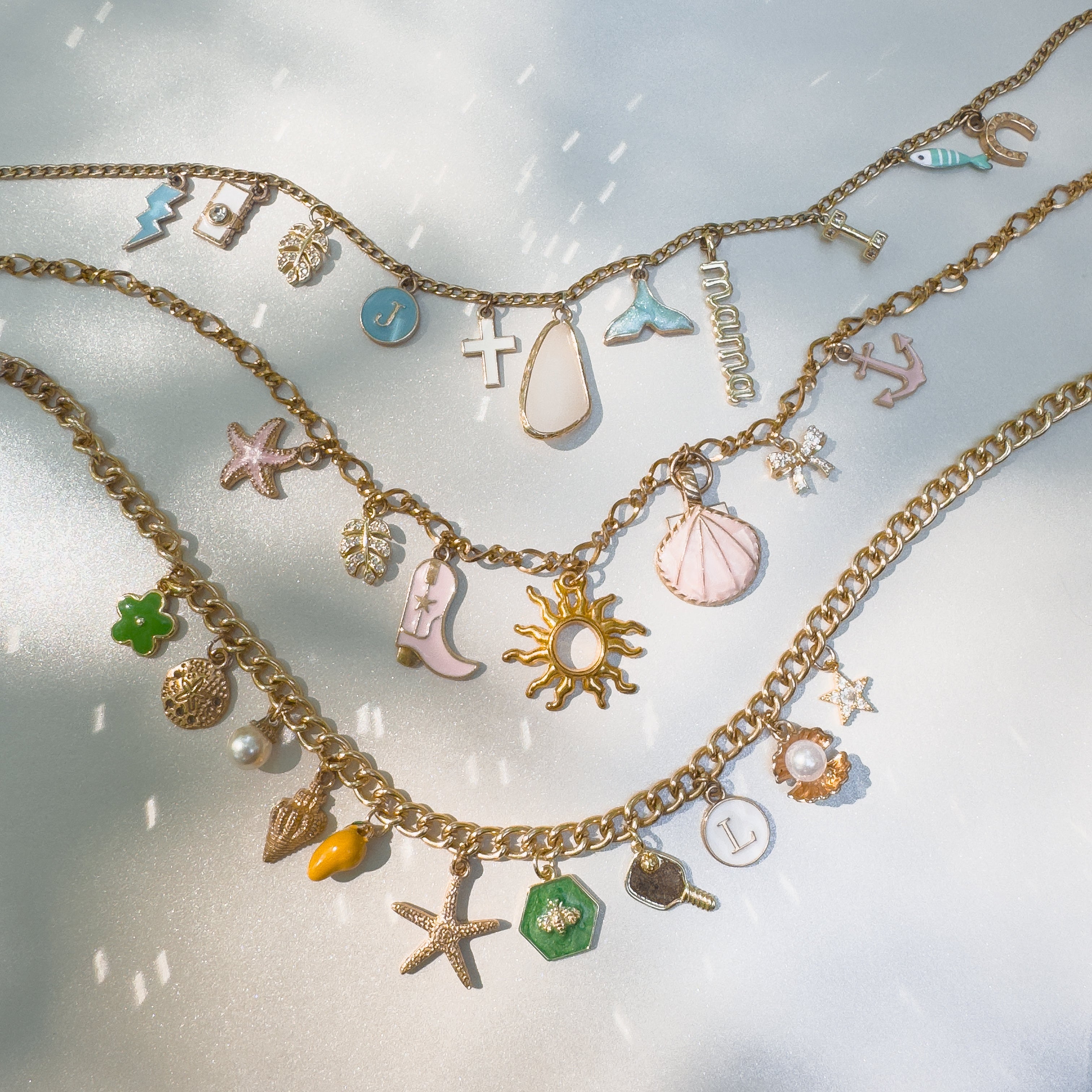 Gold necklaces with various charms on a light background