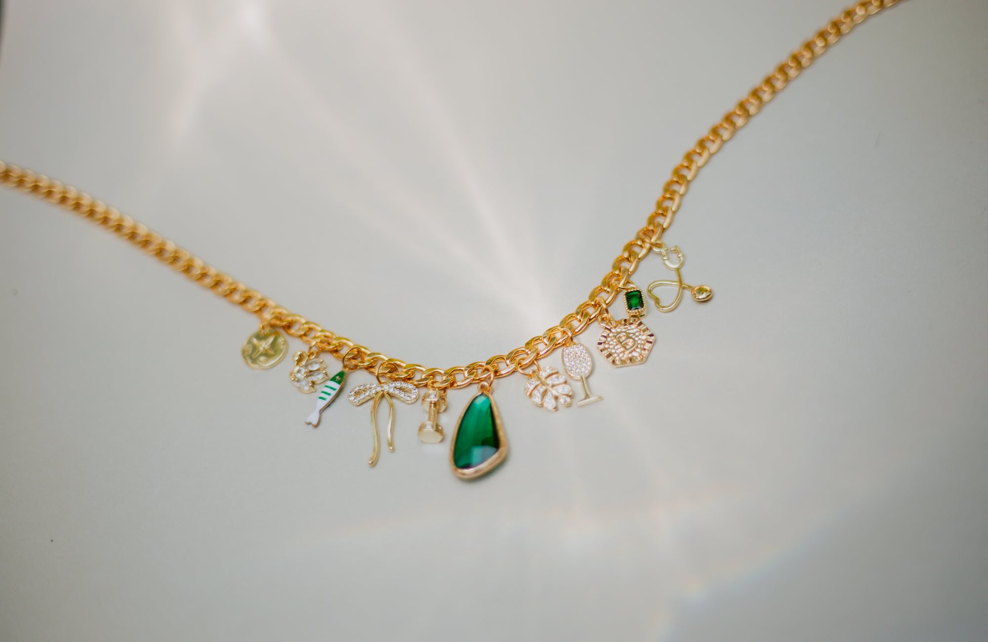 Gold necklace with various charms on a light gray background